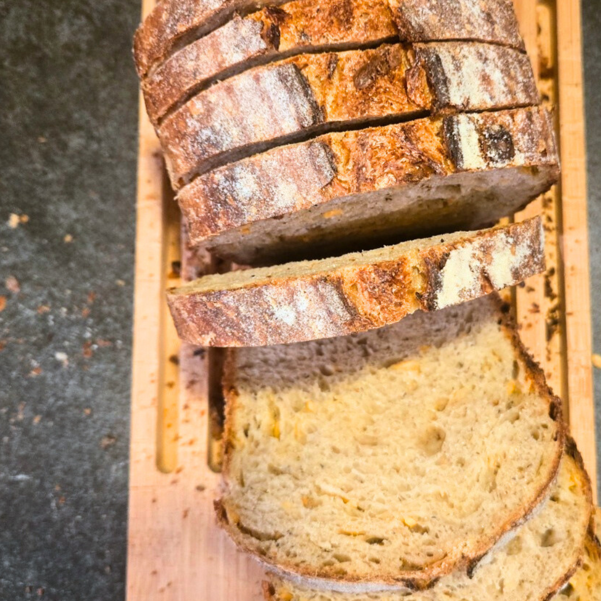 Sliced loaf of bread on a wooden cutting board with a dark background